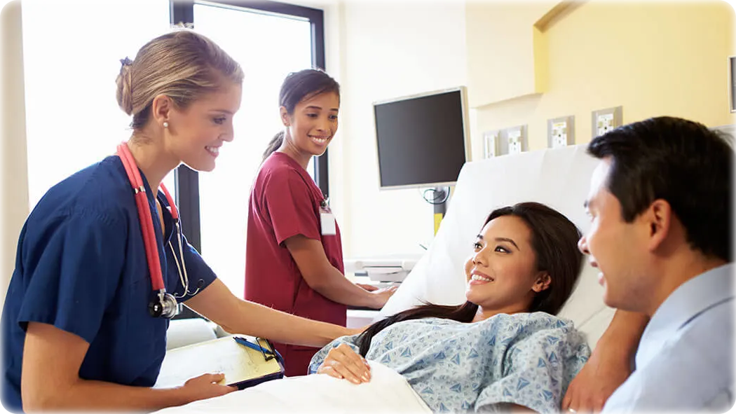 Couple at the hospital with a nurse in a red gown and a nurse in a blue gown