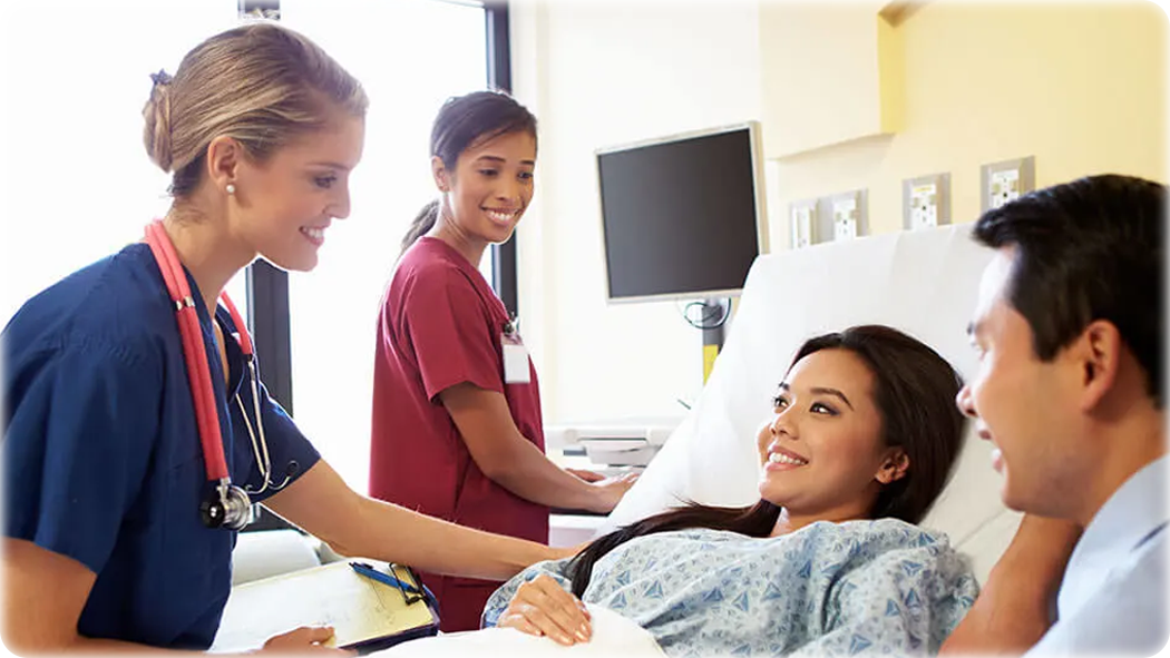 Couple at the hospital with a nurse in a red gown and a nurse in a blue gown