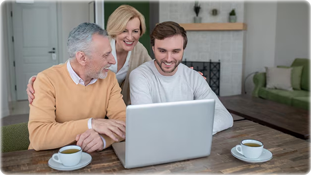 Family using their laptop together in a living room on a wooden desk with tea