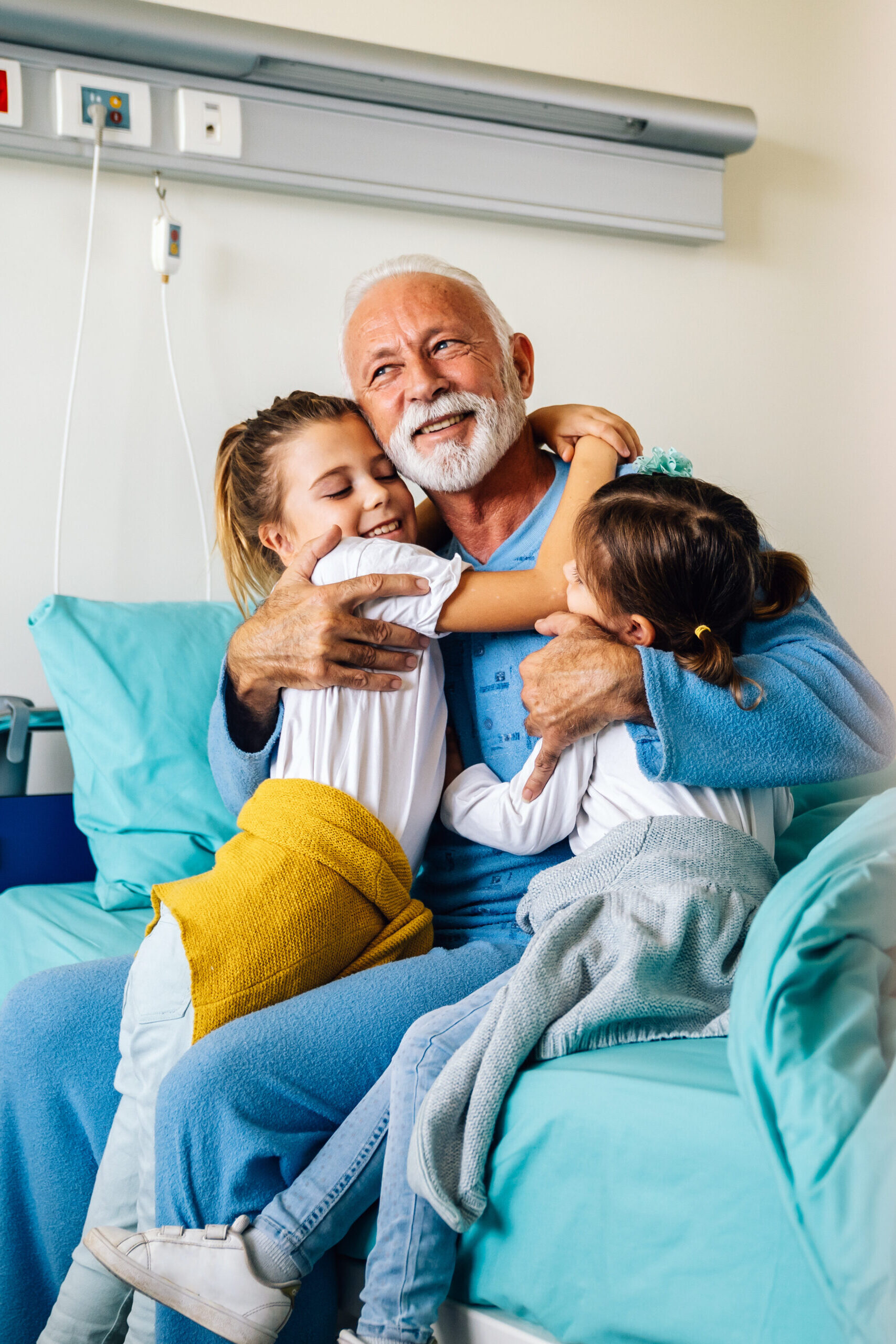 Elderly gentleman at the hospital hugging his two daughters